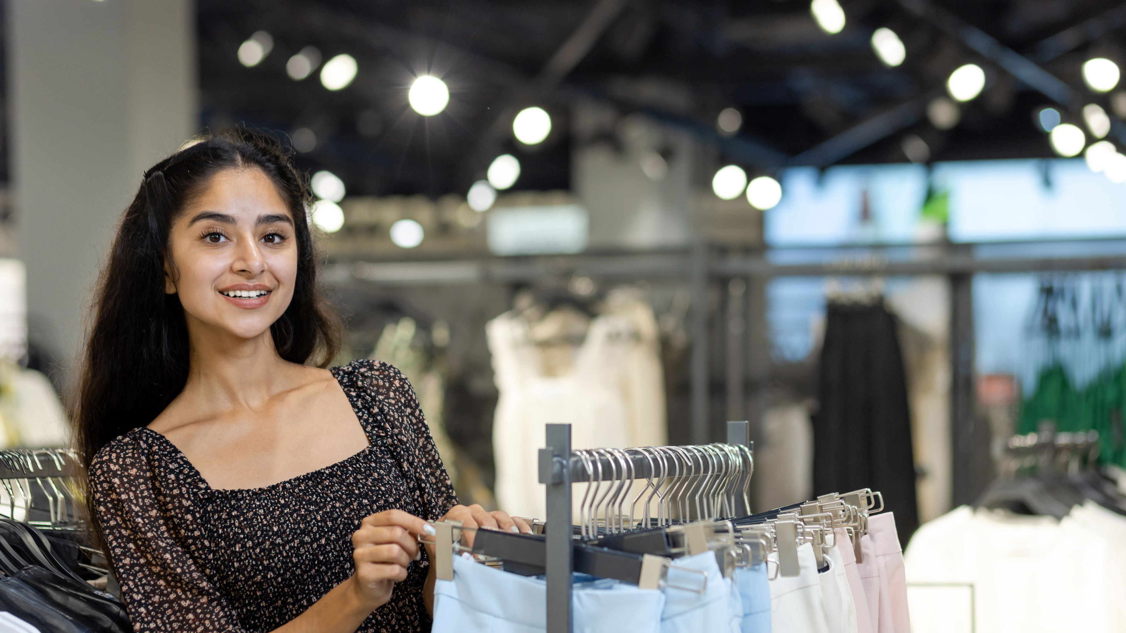 An Indian young women browsing through pants in a fashion store.